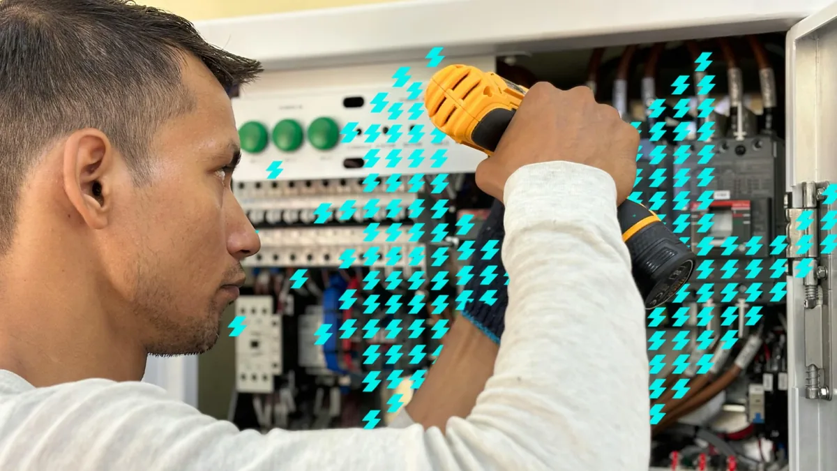 Eletricista trabalhando dentro de um quadro de comando elétrico