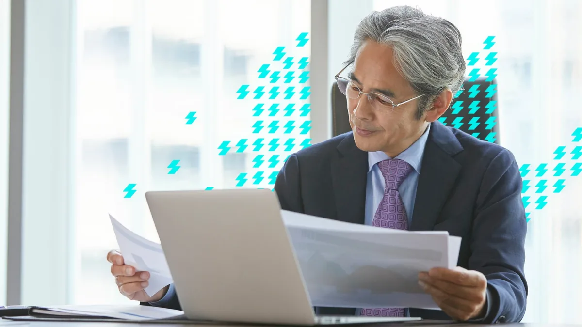 Executivo analisando relatórios impressos ao lado do notebook